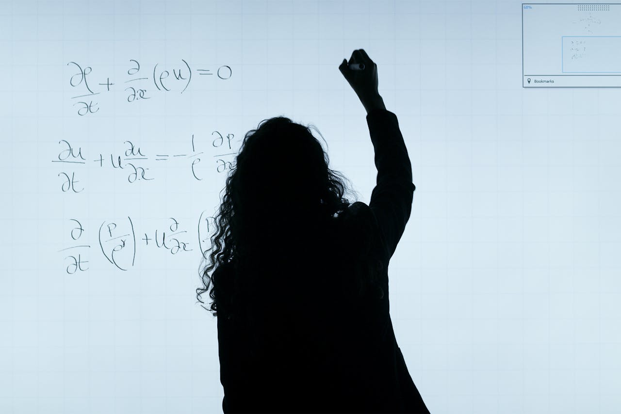 portfolio-06 A silhouette of a woman writing mathematical equations on a large whiteboard, representing education and analysis.