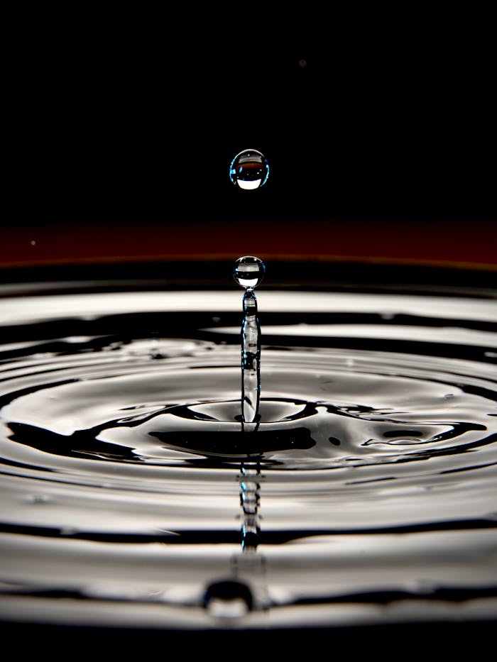Quantum Tunnelling Breaks Out of the Atomic World – and Redefines the Future Dramatic close-up of a water droplet creating ripples against a dark background, emphasizing fluid motion.